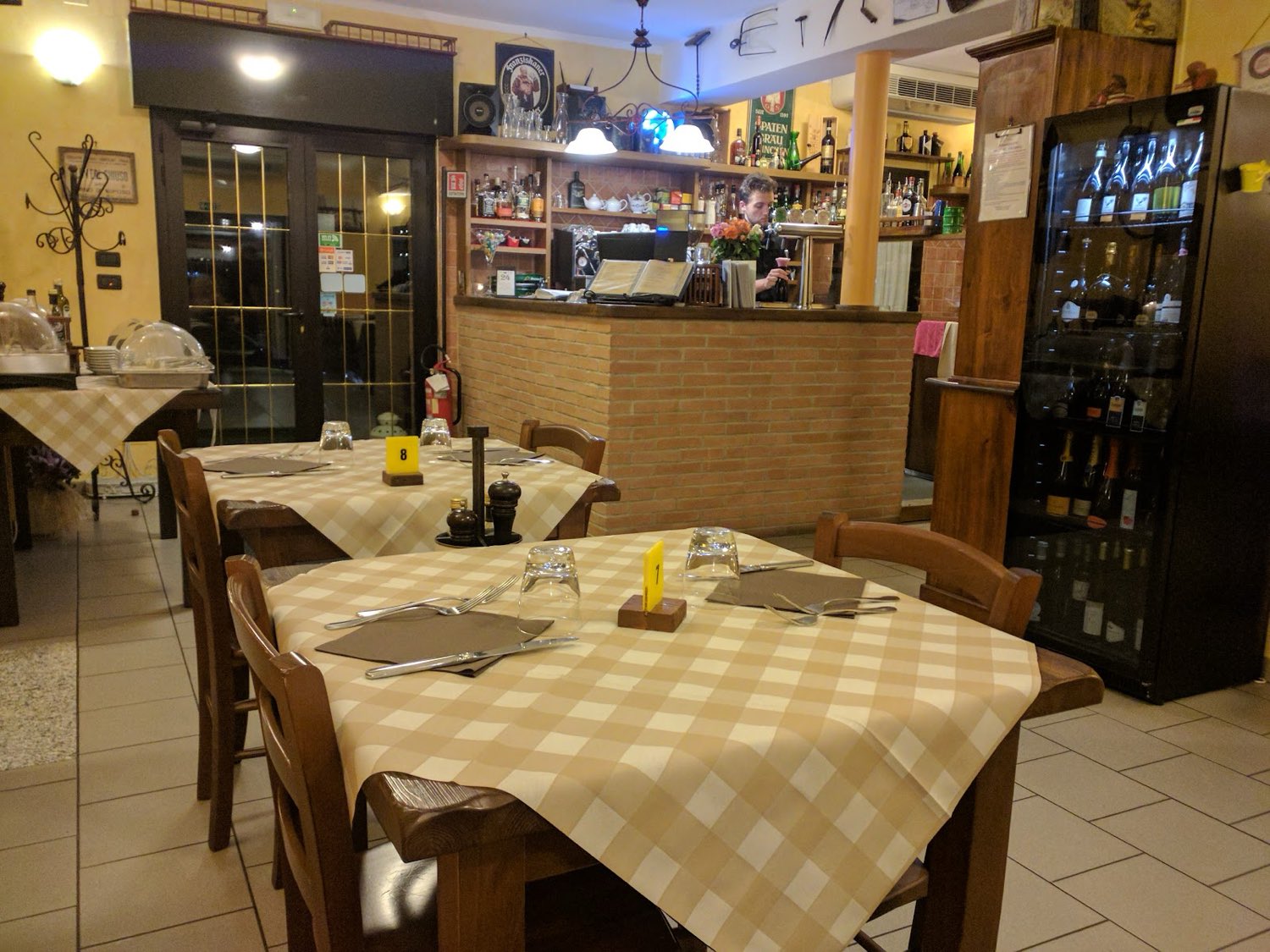 La sala del Ristorone: tavoli con tovaglie a quadri e il bancone in mattoni