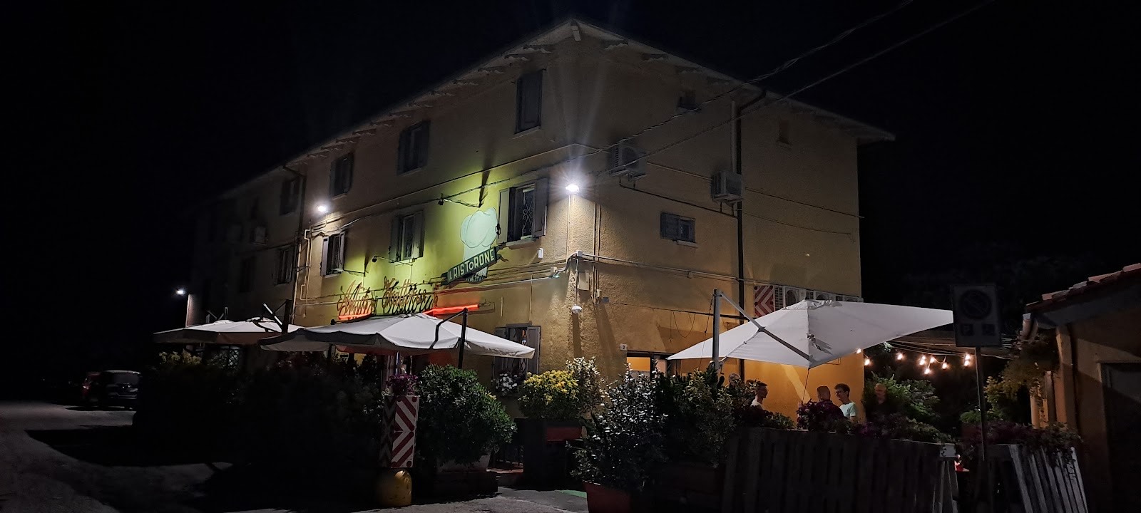 La facciata del Ristorone la sera, con i tavoli all'aperto sotto gli ombrelloni